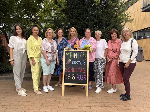 Das Team der ersten Klassen steht rund um die Einschulungstafel.