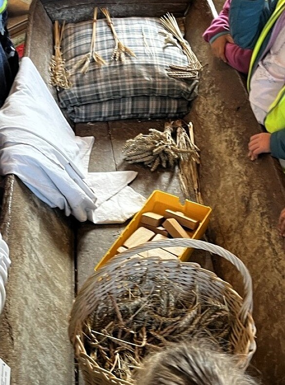 Die Kinder betrachten verschiedene Gegenstände mit Getreide. 