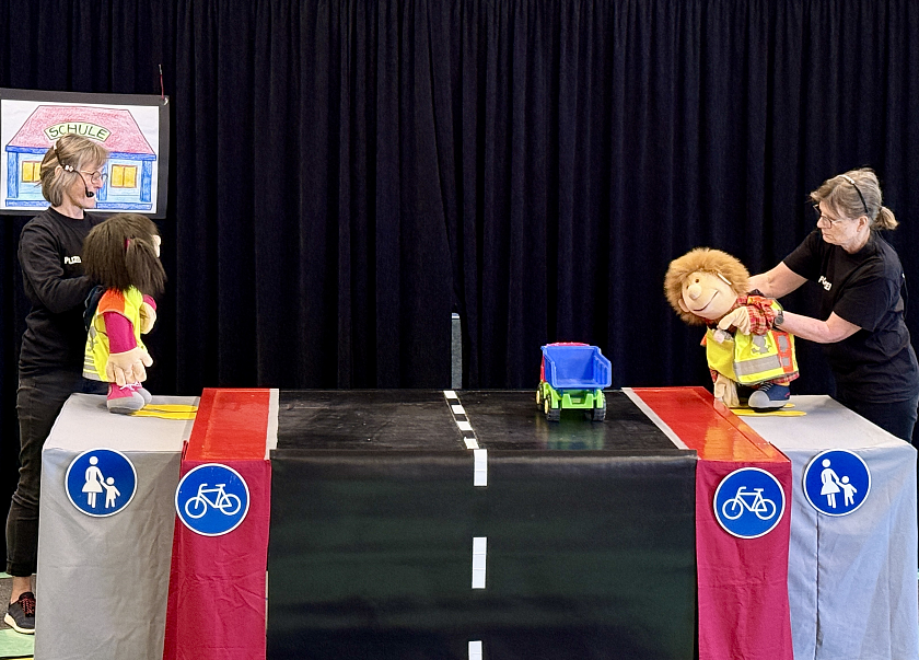 Zwei Darstellerinnen spielen mit Handpuppen Situationen im Straßenverkehr nach. 