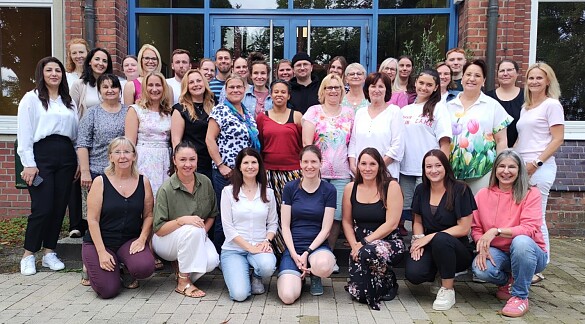 Das Team der Schule steht vor dem Altbau. 